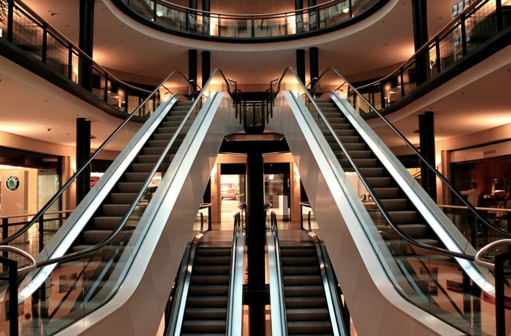 warm lit image of escalators in mall - commercial electrician